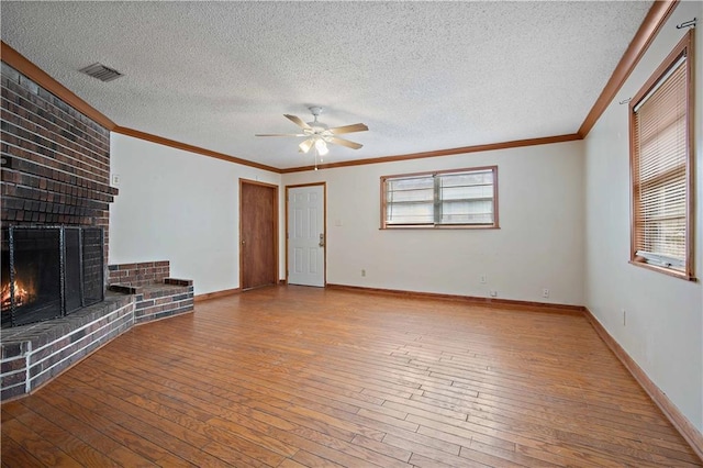 unfurnished living room with light wood-style flooring, visible vents, baseboards, a brick fireplace, and crown molding