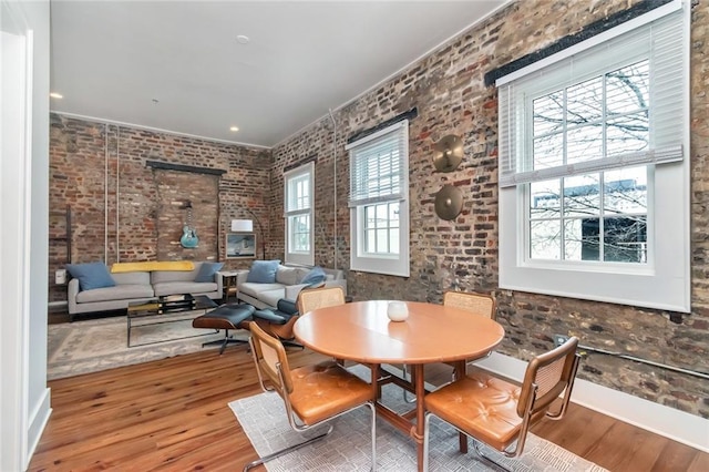 dining space featuring wood-type flooring and brick wall