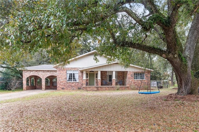 ranch-style home with driveway, brick siding, covered porch, and a ceiling fan