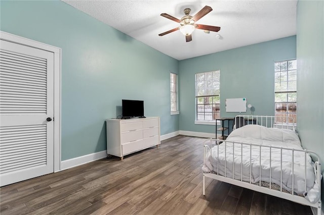 bedroom with a ceiling fan, wood finished floors, baseboards, and a textured ceiling