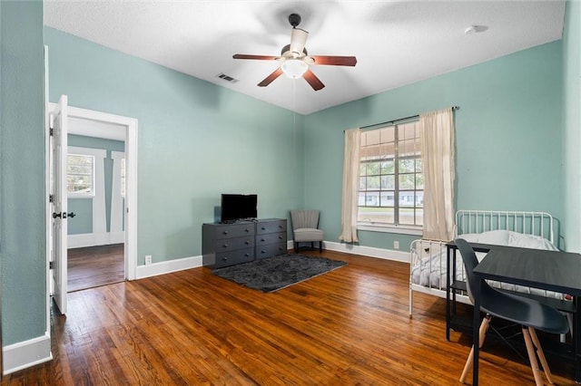 interior space with a ceiling fan, baseboards, visible vents, and wood-type flooring