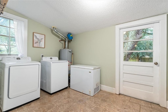 laundry room with baseboards, washing machine and dryer, gas water heater, laundry area, and a textured ceiling