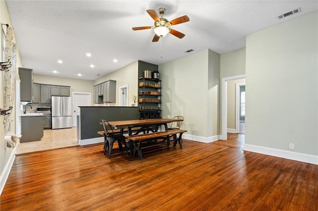 dining space with visible vents, baseboards, wood finished floors, and a ceiling fan