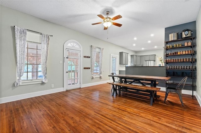 dining space featuring a textured ceiling, wood finished floors, baseboards, and ceiling fan