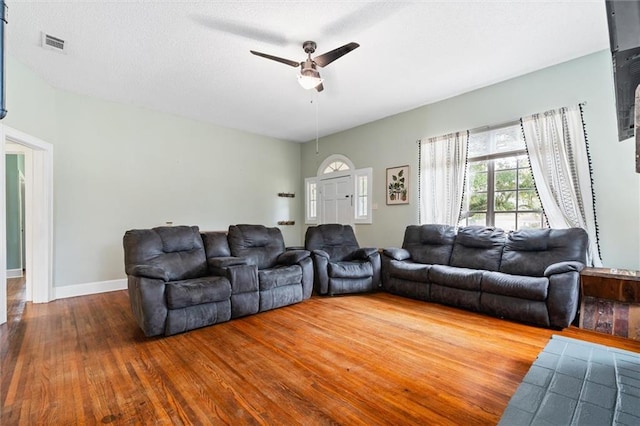 living area featuring ceiling fan, visible vents, baseboards, and wood finished floors