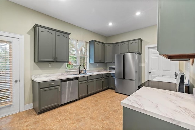 kitchen with gray cabinets, a sink, recessed lighting, stainless steel appliances, and baseboards