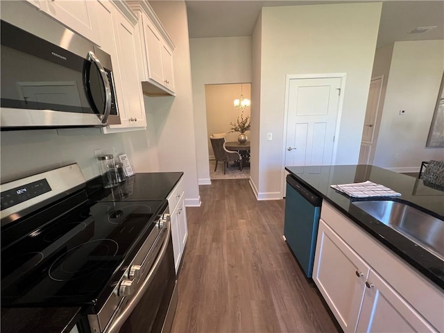 9198 Ofallon Dr N, Mobile, AL 36695 - kitchen featuring stainless steel appliances, a chandelier, dark wood-style floors, white cabinetry, and dark countertops