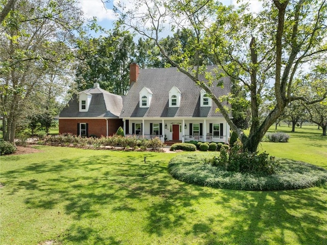 new england style home featuring covered porch and a front yard