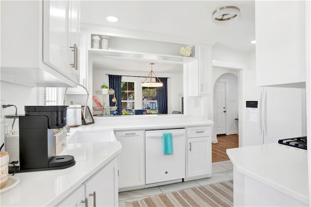 kitchen featuring sink, white cabinets, light tile patterned floors, decorative light fixtures, and white dishwasher