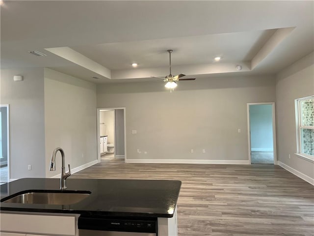 kitchen with visible vents, baseboards, a tray ceiling, and a sink