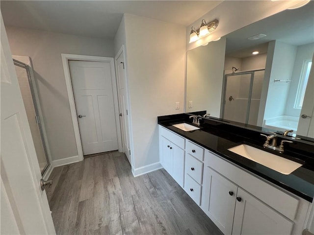 full bathroom featuring baseboards, wood finished floors, a stall shower, and a sink