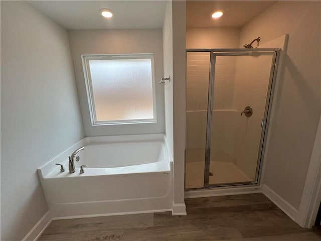 full bathroom featuring a garden tub, wood finished floors, a stall shower, and baseboards