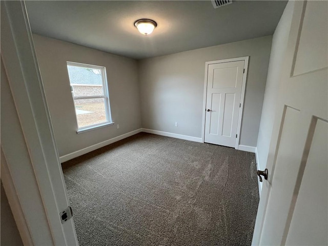 unfurnished bedroom with visible vents, baseboards, and dark colored carpet