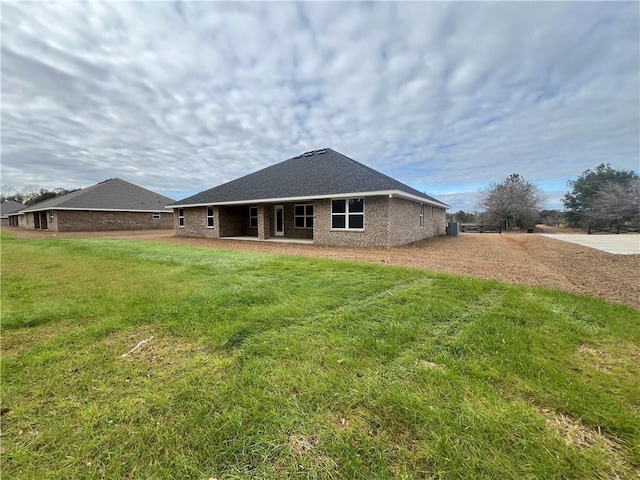 rear view of house featuring brick siding and a yard