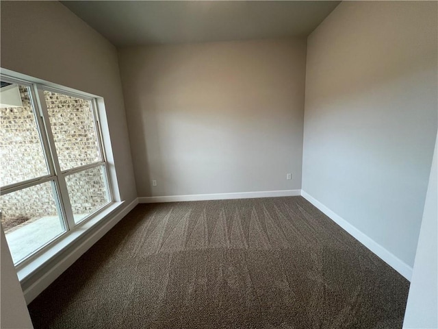 empty room with dark colored carpet and baseboards