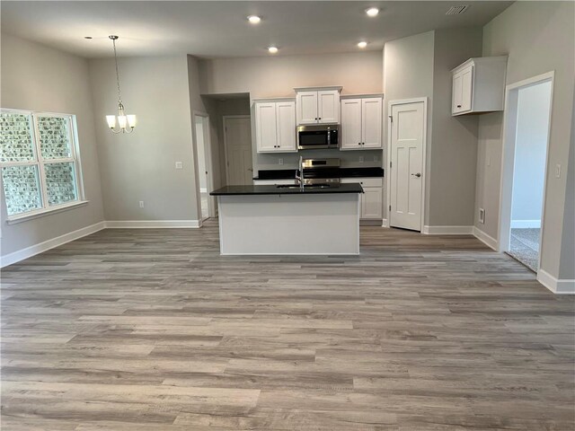 kitchen with white cabinetry, stainless steel microwave, dark countertops, and a sink