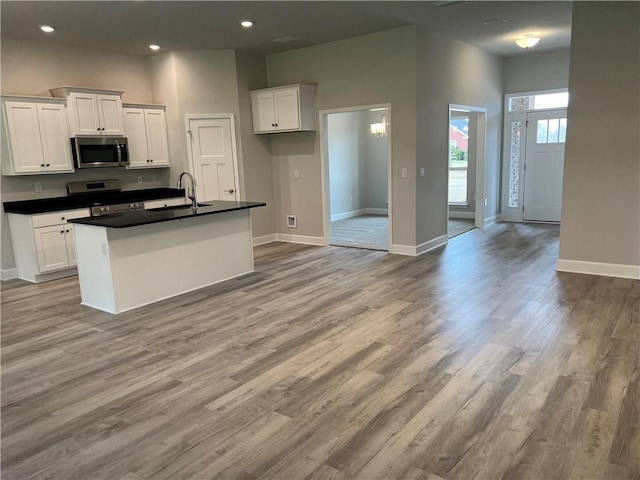 kitchen featuring a sink, dark countertops, white cabinetry, appliances with stainless steel finishes, and baseboards