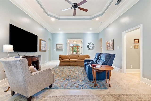 living area with visible vents, ornamental molding, arched walkways, a raised ceiling, and ceiling fan