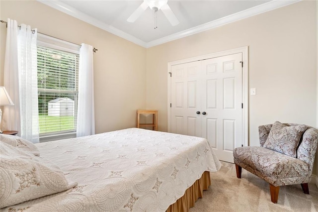 bedroom featuring a ceiling fan, light colored carpet, a closet, and ornamental molding