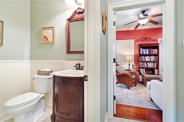 ensuite bathroom with a wainscoted wall, toilet, a ceiling fan, ensuite bath, and vanity