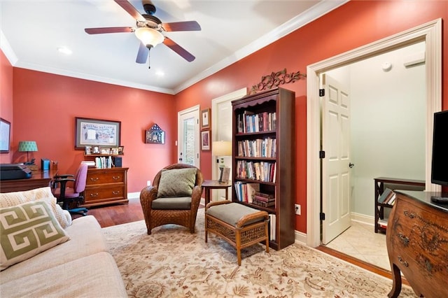 interior space featuring wood finished floors, a ceiling fan, baseboards, and ornamental molding