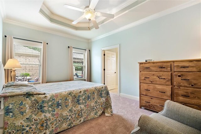 bedroom featuring light carpet, a raised ceiling, ornamental molding, a ceiling fan, and baseboards