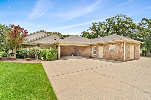 single story home featuring brick siding, a shingled roof, a front lawn, and fence