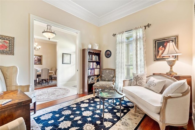 sitting room featuring baseboards, wood finished floors, a notable chandelier, and ornamental molding