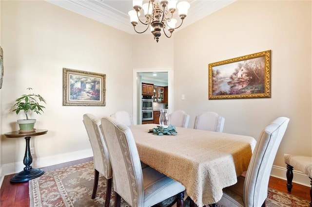 dining space featuring ornamental molding, baseboards, an inviting chandelier, and wood finished floors