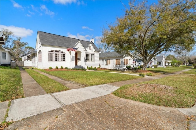 view of front of house featuring brick siding, a chimney, and a front yard