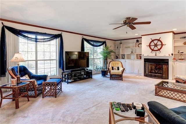 carpeted living room with ceiling fan, crown molding, and built in features