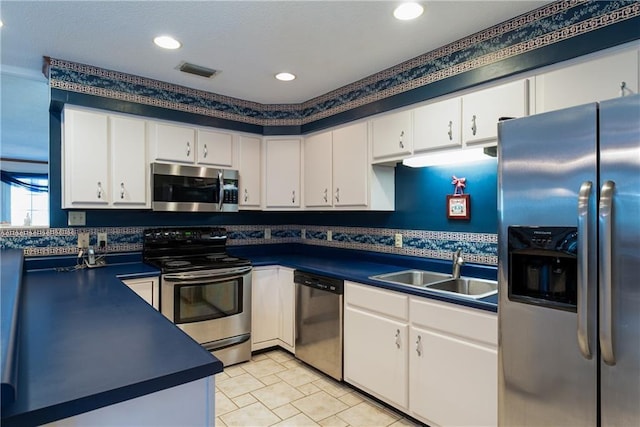 kitchen featuring sink, stainless steel appliances, light tile floors, and white cabinetry