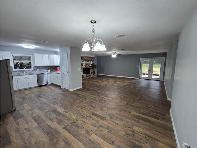 kitchen featuring white cabinetry, a brick fireplace, tasteful backsplash, pendant lighting, and appliances with stainless steel finishes