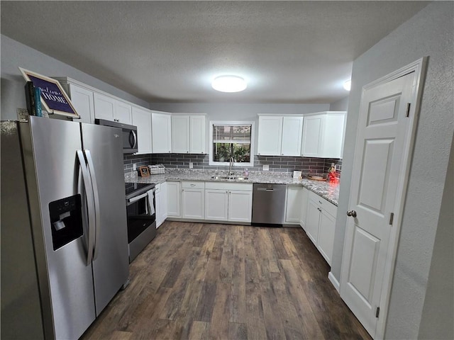 kitchen featuring light stone countertops, sink, stainless steel appliances, backsplash, and white cabinets