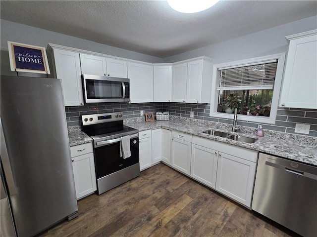 kitchen featuring light stone countertops, white cabinetry, sink, and appliances with stainless steel finishes