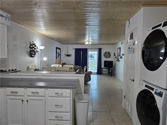 kitchen with wooden ceiling, light tile patterned floors, white cabinets, and stacked washing maching and dryer