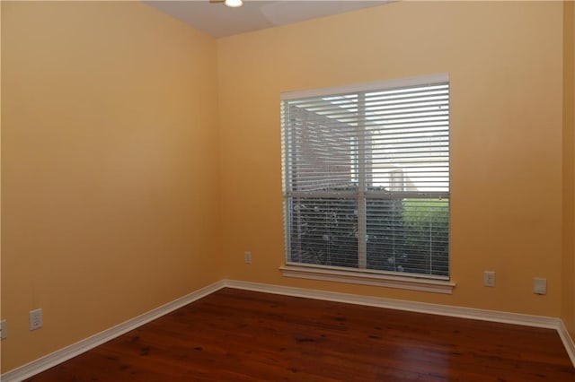 spare room with baseboards and dark wood finished floors