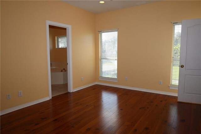 spare room with dark wood-type flooring, plenty of natural light, recessed lighting, and baseboards