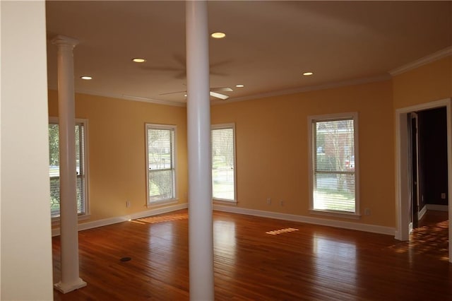 empty room featuring crown molding, ceiling fan, baseboards, wood finished floors, and ornate columns