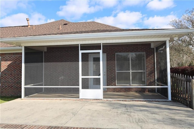 back of property with brick siding, roof with shingles, and a sunroom