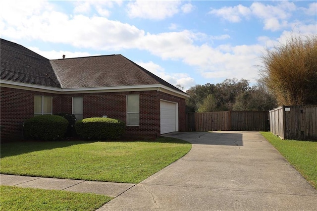 view of side of property with brick siding, an attached garage, fence, a yard, and driveway