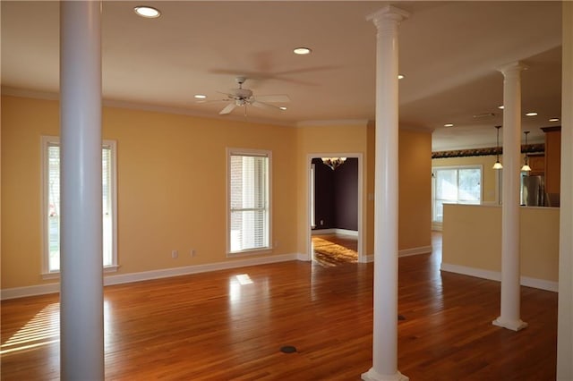 unfurnished living room featuring decorative columns, baseboards, wood finished floors, and crown molding