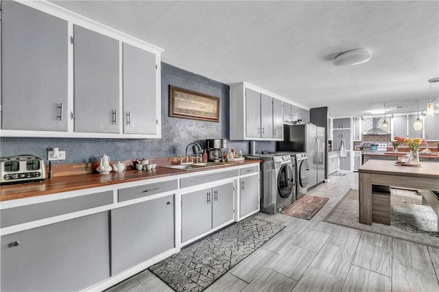 18127 County Road 10th Rd, Foley, AL 36535 - kitchen with wooden counters, wall chimney exhaust hood, tasteful backsplash, a sink, and independent washer and dryer