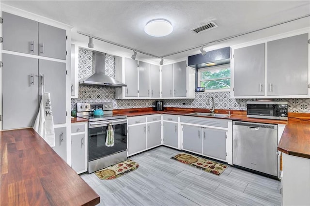 18127 County Road 10th Rd, Foley, AL 36535 - kitchen featuring wall chimney range hood, appliances with stainless steel finishes, track lighting, a sink, and decorative backsplash