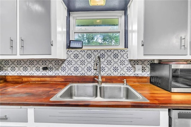 18127 County Road 10th Rd, Foley, AL 36535 - kitchen featuring white cabinets, a sink, butcher block countertops, stainless steel microwave, and decorative backsplash