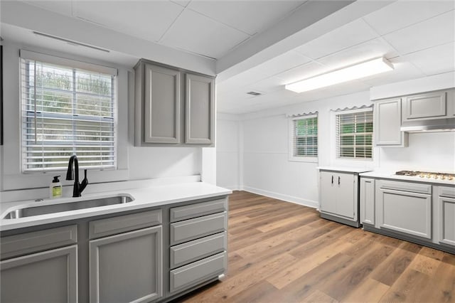 kitchen featuring dark hardwood / wood-style floors, gray cabinets, sink, and gas cooktop