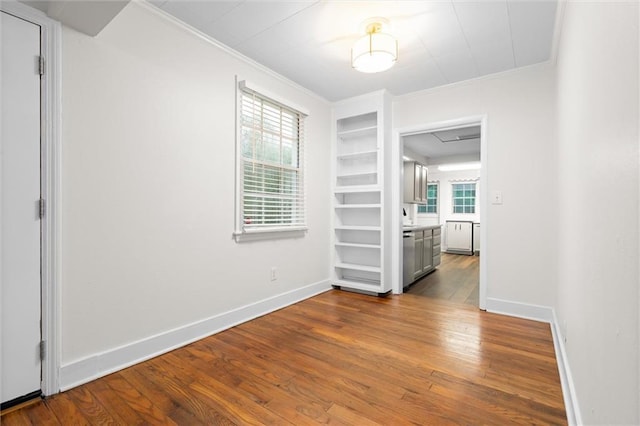 spare room with hardwood / wood-style flooring, built in features, and crown molding