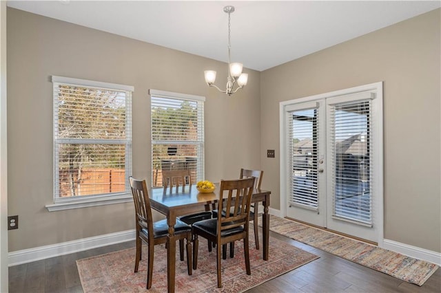 dining area featuring dark wood-type flooring, a wealth of natural light, and a notable chandelier