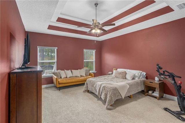 carpeted bedroom featuring ceiling fan, ornamental molding, and a tray ceiling