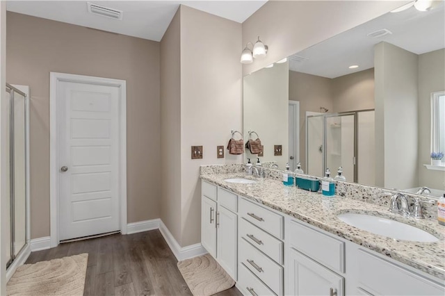 bathroom with vanity, a shower with shower door, and wood-type flooring